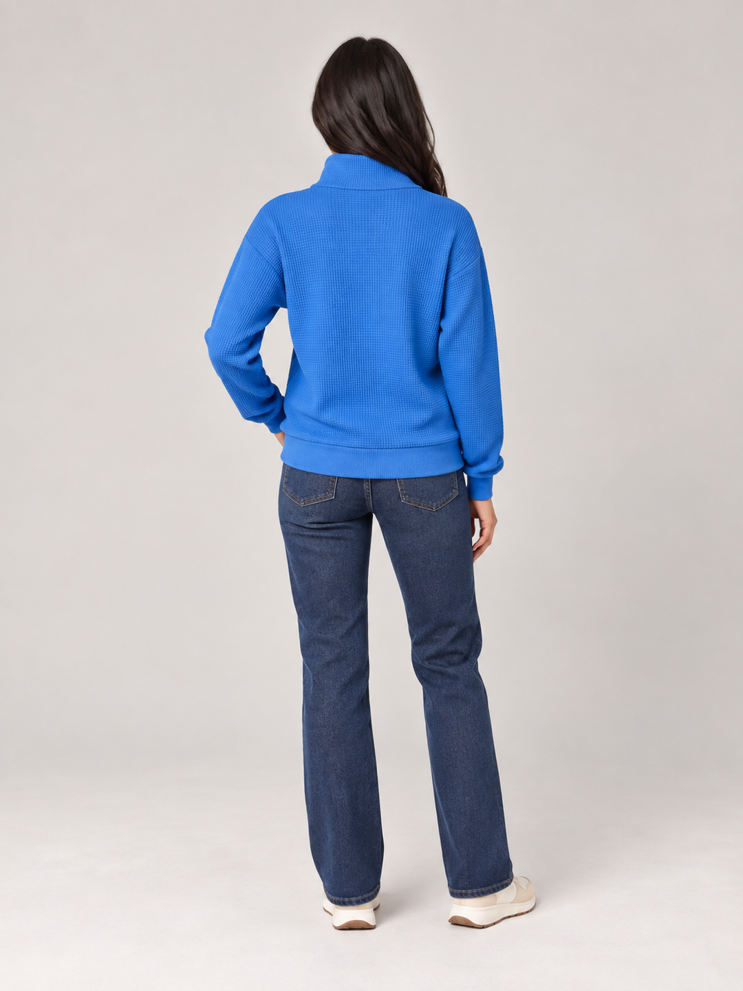 Back view of a bright blue relaxed-fit waffle knit half-zip jumper paired with classic blue denim jeans.