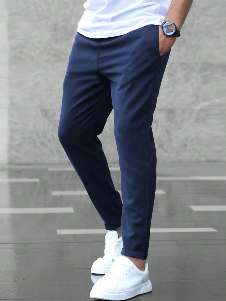 Men wearing navy blue slim-fit joggers with a drawstring waist and side pockets, paired with white sneakers.