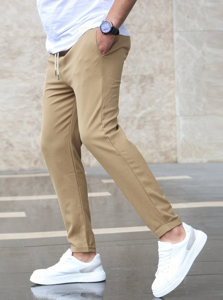 Men wearing tan slim-fit drawstring joggers with side pockets and white sneakers for a modern casual look.