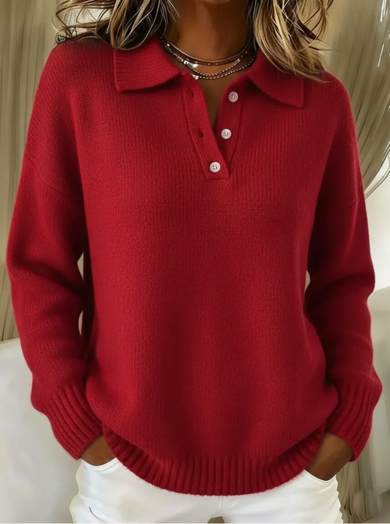 Relaxed red knit polo jumper with a collared neckline, button placket, and ribbed cuffs worn with white trousers.