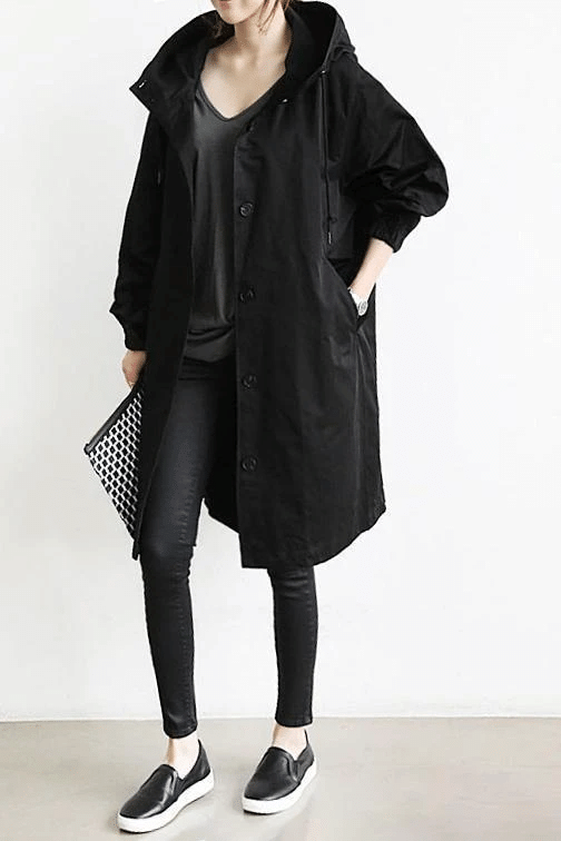 Black longline windbreaker jacket with an adjustable hood, button-front closure, and elasticated cuffs.