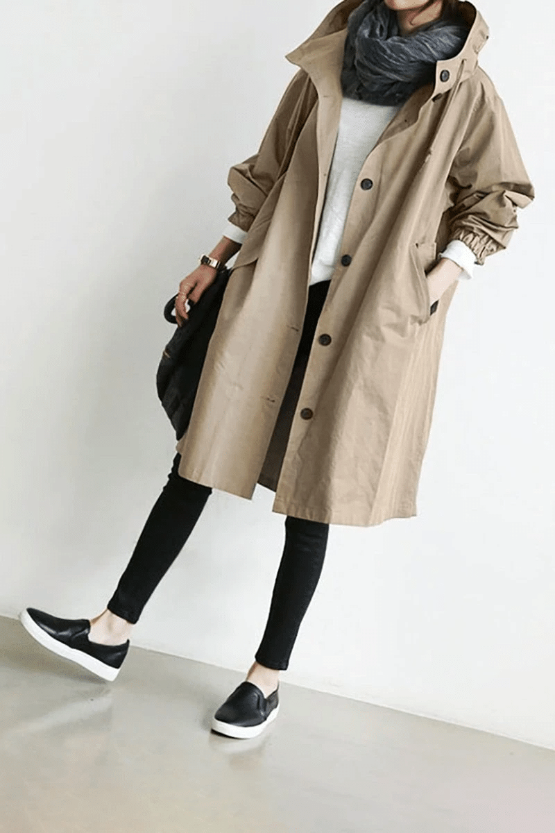 Beige longline hooded windbreaker with button front, elasticated cuffs, and side pockets worn over black leggings.