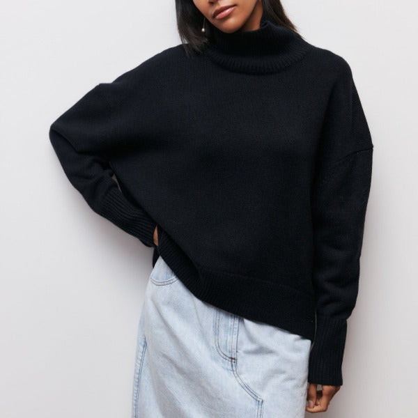Black oversized turtleneck jumper with dropped shoulders and ribbed cuffs worn with light-wash denim.