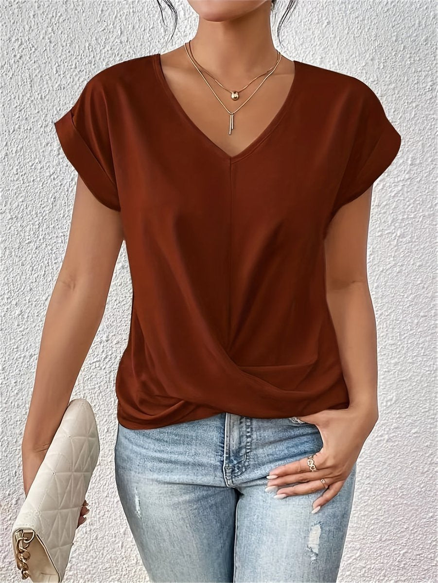 Rust-colored V-neck top with cap sleeves and a flattering twist hem detail, styled with light wash jeans.