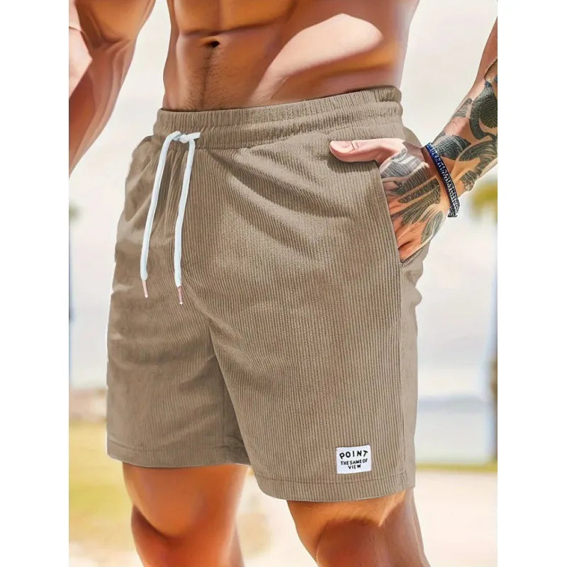Beige corduroy men's drawstring shorts with side pockets and a small branded patch on the hem.