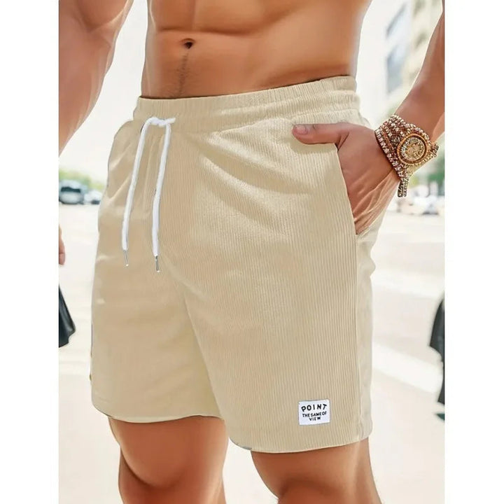 Beige corduroy men's drawstring shorts with side pockets and a small branded patch on the hem.