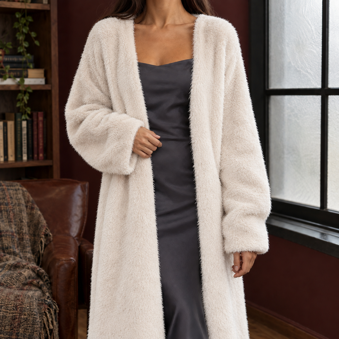 Cream-colored plush knit longline cardigan with an open front and relaxed fit, layered over a dark grey slip dress.