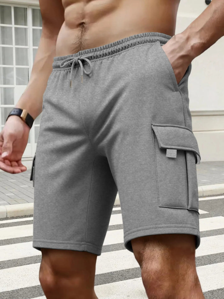 Grey men's cargo shorts with an elastic drawstring waist and side flap pockets, featuring a comfortable knee-length fit.