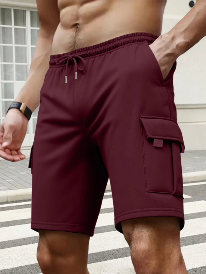 Men’s maroon cargo shorts featuring an elasticated drawstring waist and side flap pockets for a relaxed fit.
