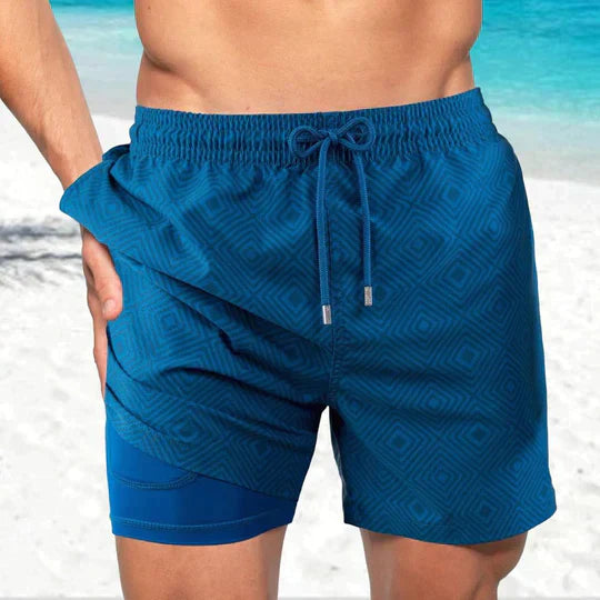 Blue geometric print swim shorts with an elastic drawstring waist and supportive inner liner with a side pocket.