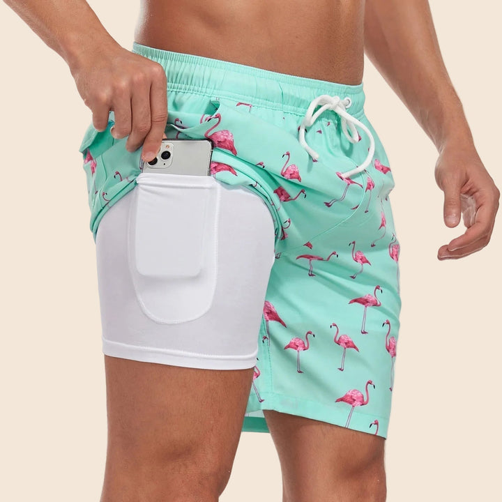 Mint green swim shorts with a pink flamingo print, featuring a white built-in liner with a convenient phone pocket.