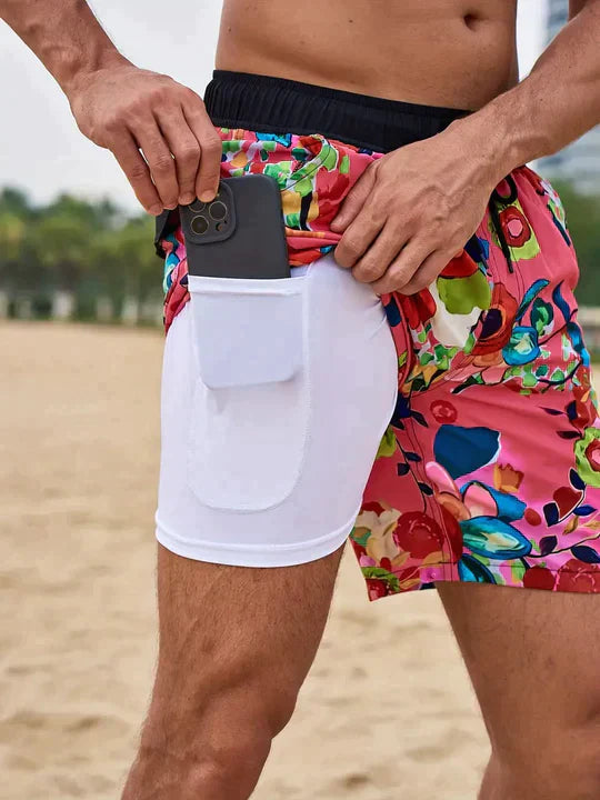 Men's pink floral swim shorts with an elastic drawstring waist and a white built-in liner featuring a side phone pocket.