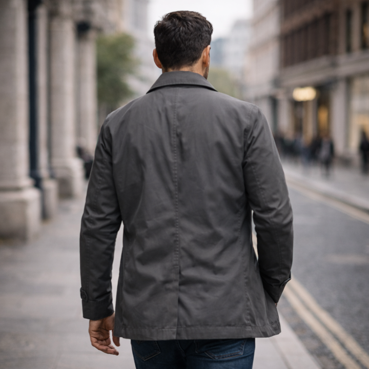 Man wearing a grey, water-resistant George windproof jacket with a polished mid-length cut while walking in the city.