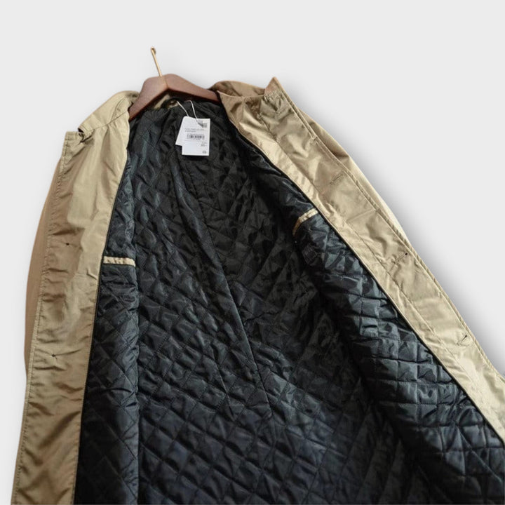 Lightweight beige windproof jacket with a refined point collar and a warm, black quilted interior lining.