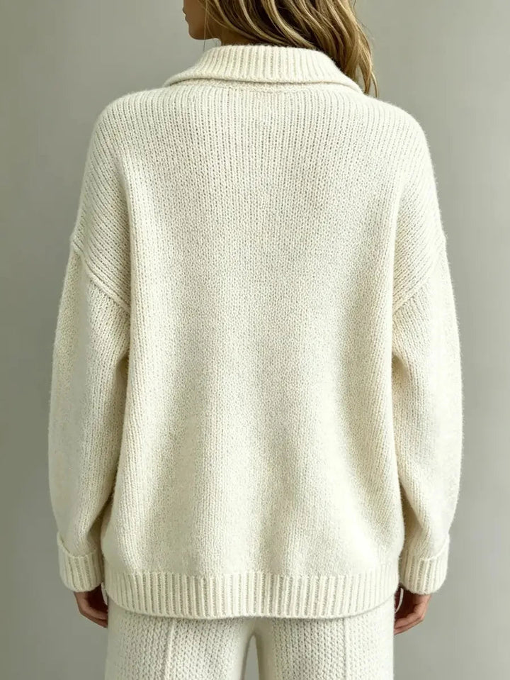 Back view of a cream-colored, textured knit polo jumper with a pointed collar, dropped shoulders, and ribbed hem.