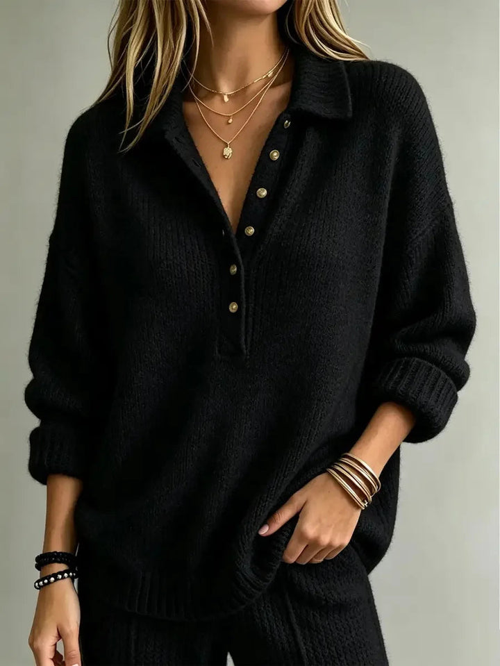 Black textured knit polo jumper with a pointed collar, partial button placket, dropped shoulders, and ribbed cuffs.