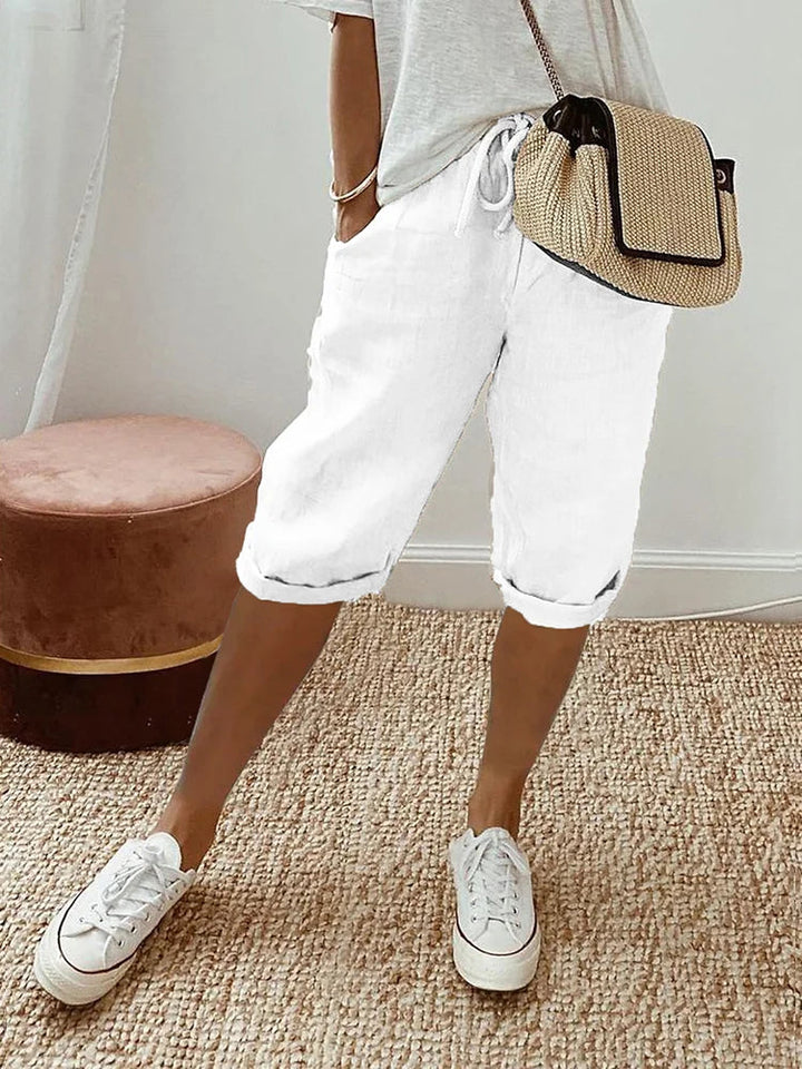 White linen drawstring shorts with rolled cuffs, side pockets, and a relaxed fit for effortless daily dressing.