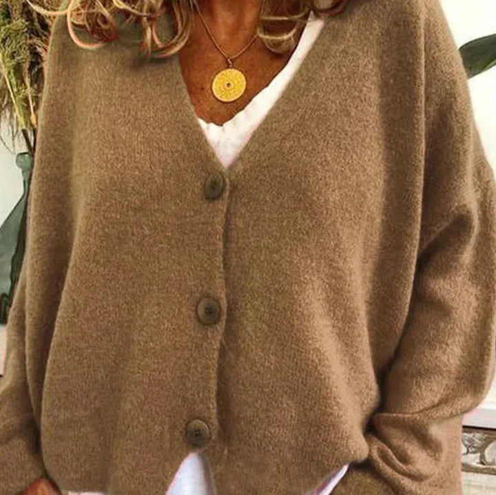 Soft brown knit V-neck cardigan with a button-front closure and relaxed, comfortable fit worn over a white top.