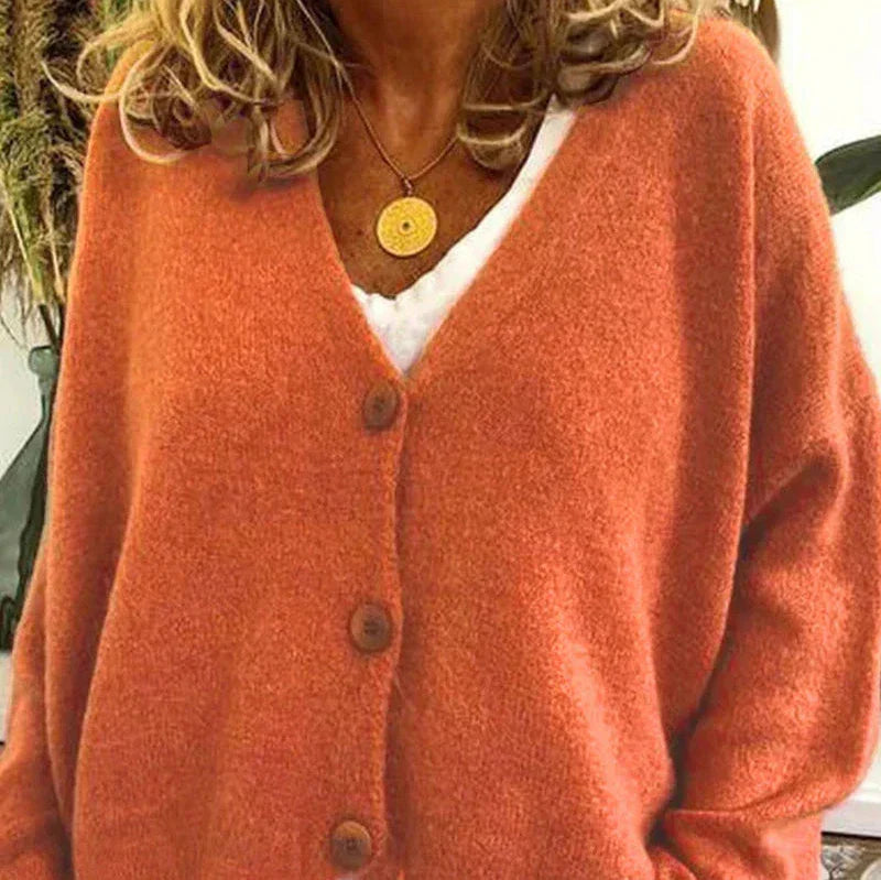 Soft orange V-neck knit cardigan with a button-down front and relaxed fit, layered over a white top.