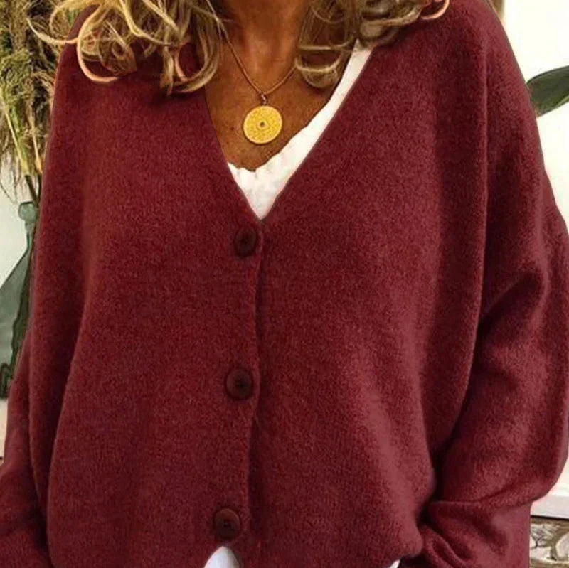 Burgundy V-neck knit cardigan with a button-front closure and relaxed fit, worn over a white top with a gold necklace.