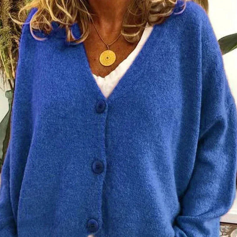 Soft blue knit V-neck cardigan with a button-front closure and relaxed fit, worn over a white top with a gold necklace.
