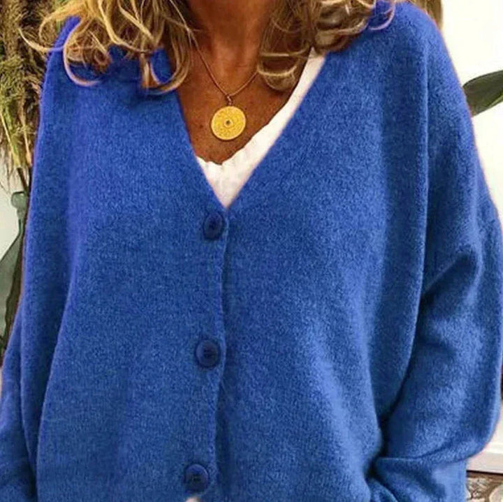 Soft blue knit V-neck cardigan with a button-front closure and relaxed fit, worn over a white top with a gold necklace.