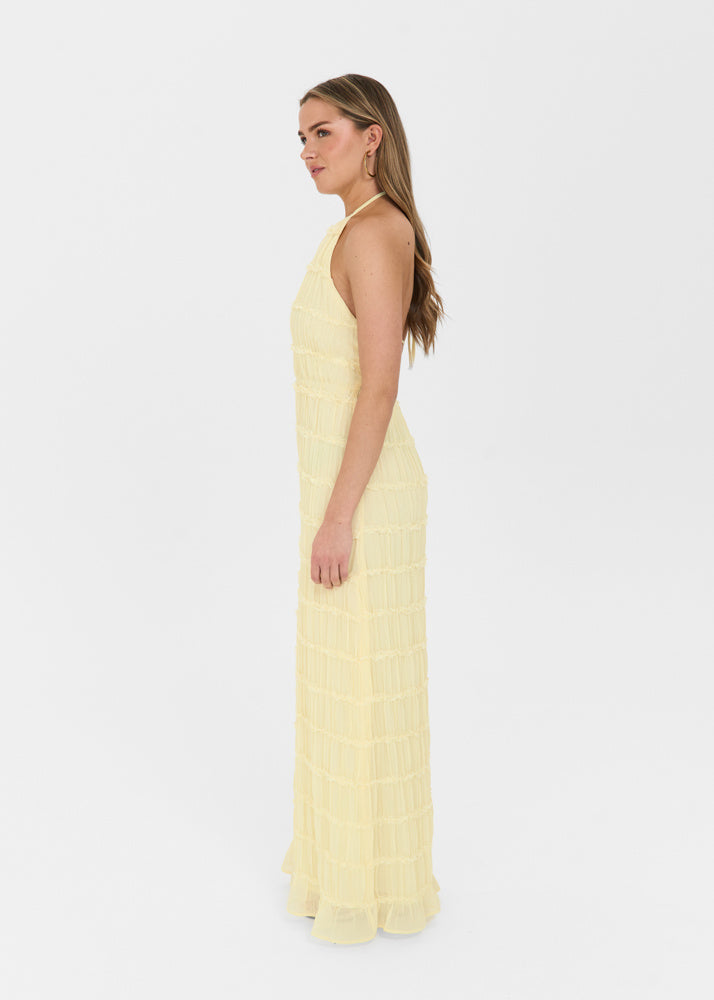 Cream-colored halter maxi dress with a textured, tiered design and open back, shown from a side profile view.