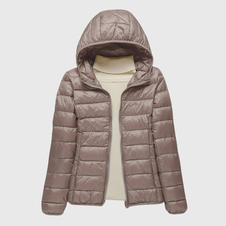 Taupe lightweight quilted hooded jacket with a slim fit and zip front, layered over a cream turtleneck sweater.