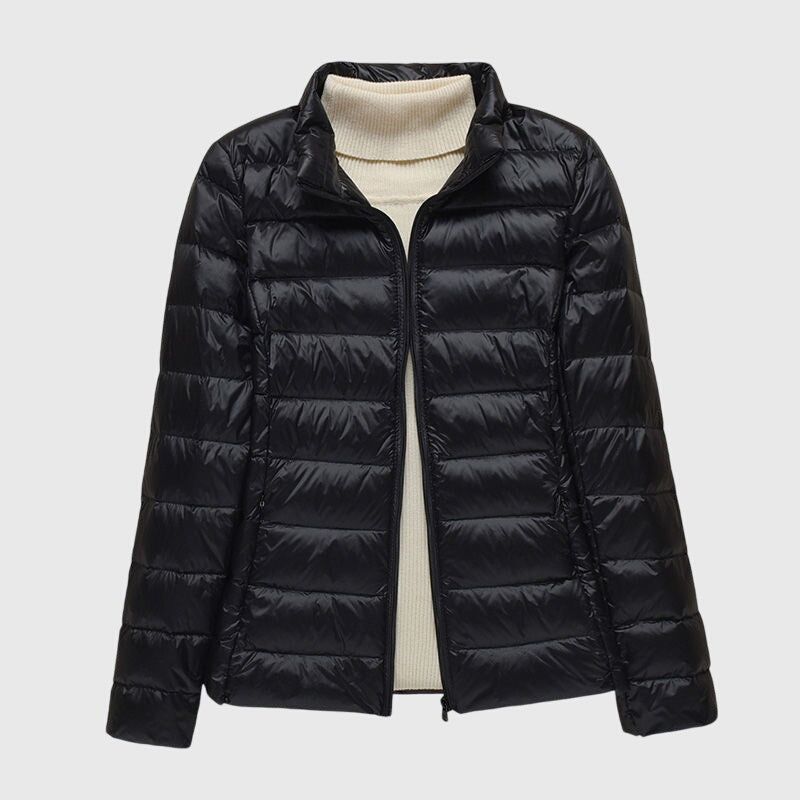 Black lightweight quilted jacket with a zip-up front, worn over a cream-colored turtleneck sweater.