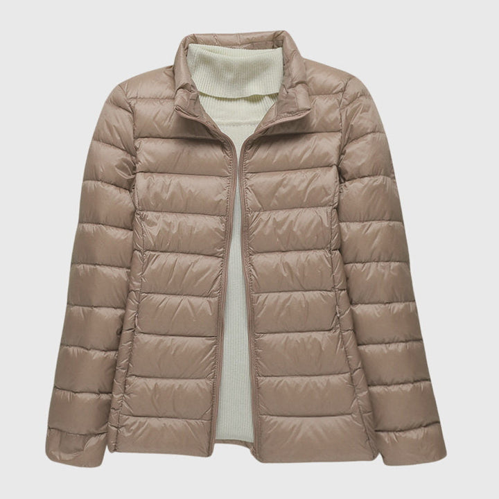 Taupe women's lightweight quilted jacket with a zip-up stand collar, layered over a cream ribbed knit sweater.