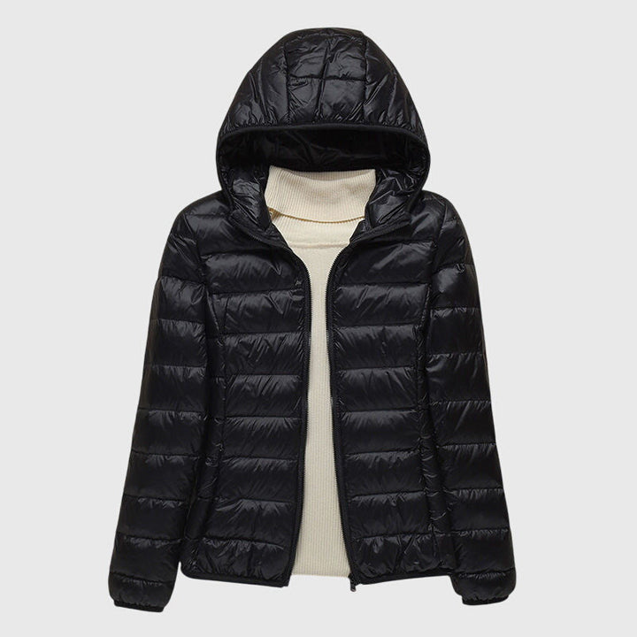 Black lightweight quilted hooded jacket with a full-length zip, layered over a cream turtleneck sweater.