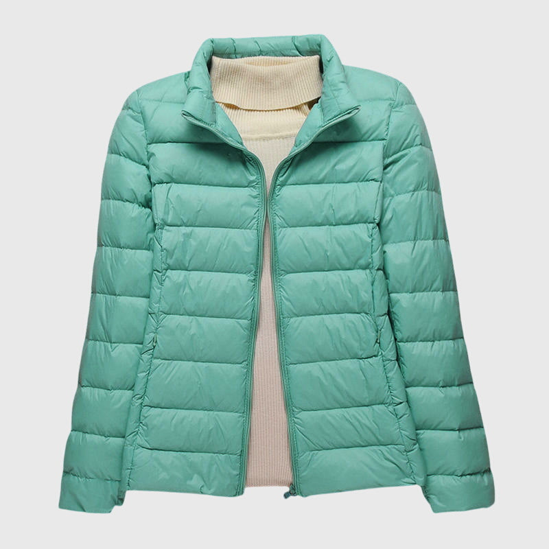 Lightweight mint green quilted jacket with a stand-up collar and zip front, layered over a cream turtleneck sweater.