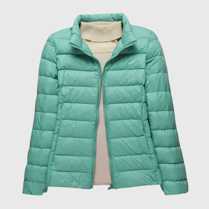Lightweight mint green quilted jacket with a stand-up collar and zip front, layered over a cream turtleneck sweater.