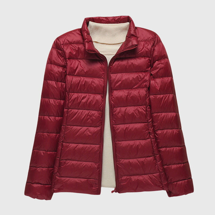 Women's lightweight, quilted burgundy jacket with a stand-up collar and full-length zip, layered over a cream sweater.
