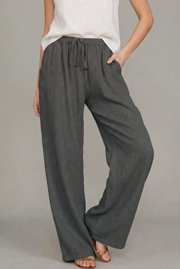 Charcoal grey wide-leg linen trousers featuring an elasticated drawstring waist and side pockets.