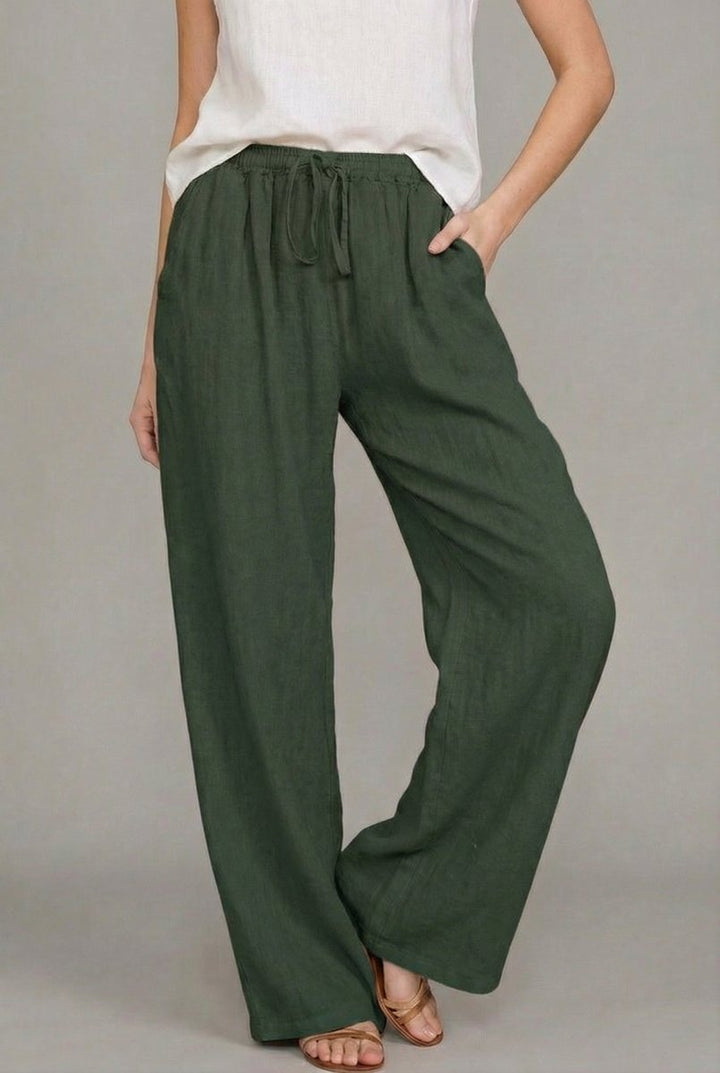 Dark green wide-leg linen trousers with an elasticated drawstring waist and side pockets on a model.