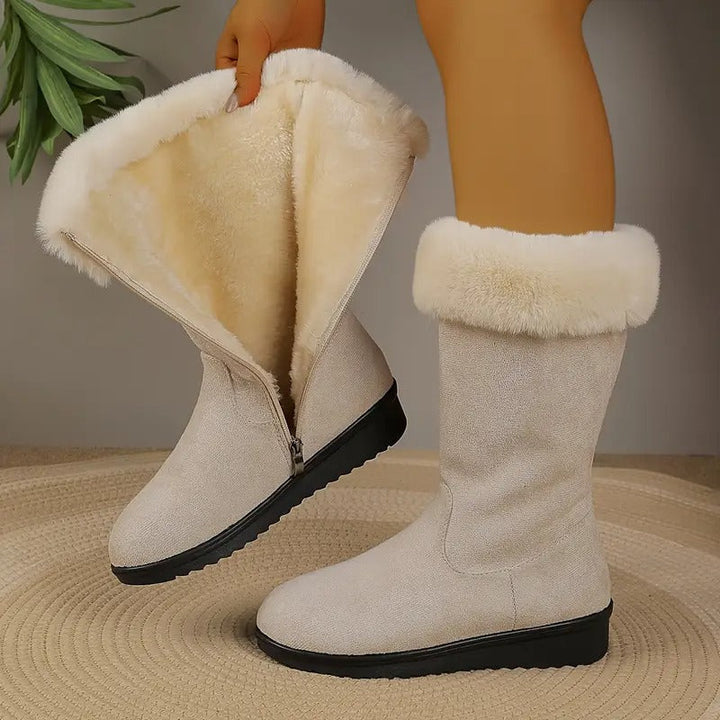 Beige mid-calf winter boots with plush faux fur lining, a folded cuff, side zip closure, and a durable black textured sole.