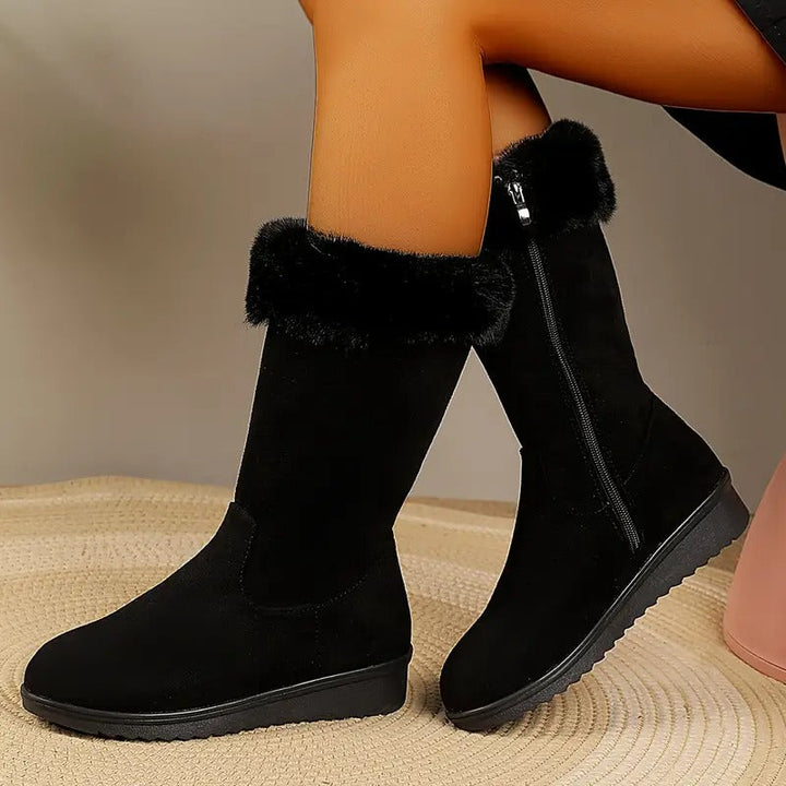 Black mid-calf winter boots featuring a plush faux fur cuff, side zip closure, and a textured grippy sole.