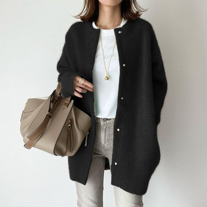 Black oversized longline cardigan with a collarless neckline and brushed knit texture, styled over a white tee and jeans.