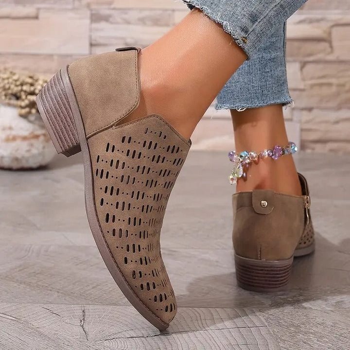 Taupe suede Harriet ankle boots featuring a breathable laser-cut design, side zip, and comfortable low block heel.