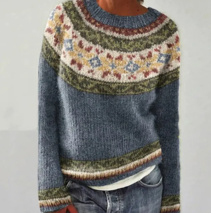 Blue Nordic knit jumper with a colourful patterned yoke, boat neckline, and relaxed fit worn with jeans.