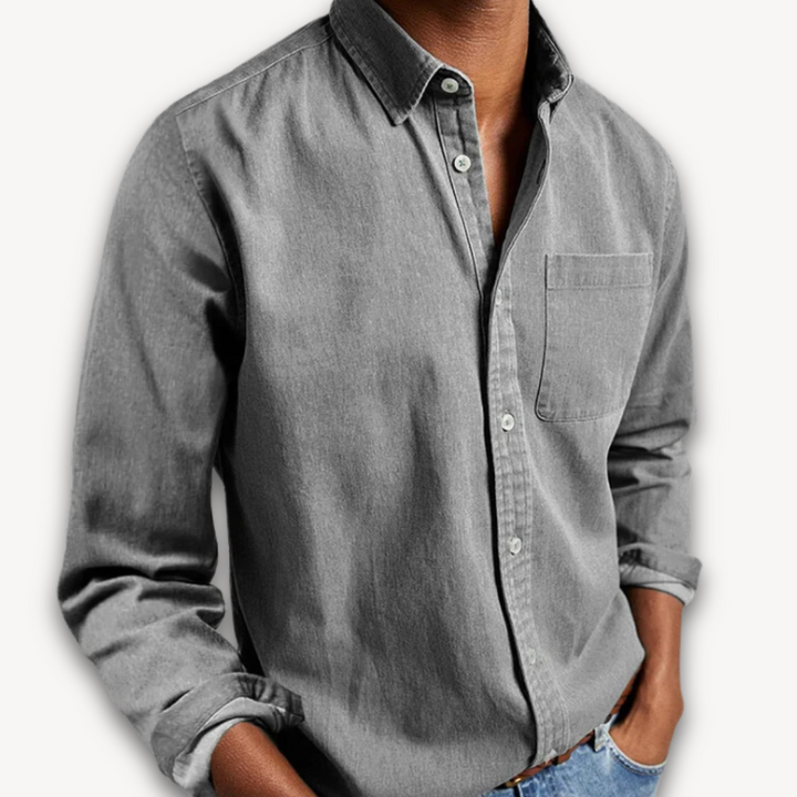 Men's grey long-sleeve button-up shirt with a classic collar and chest pocket, worn with sleeves slightly rolled.