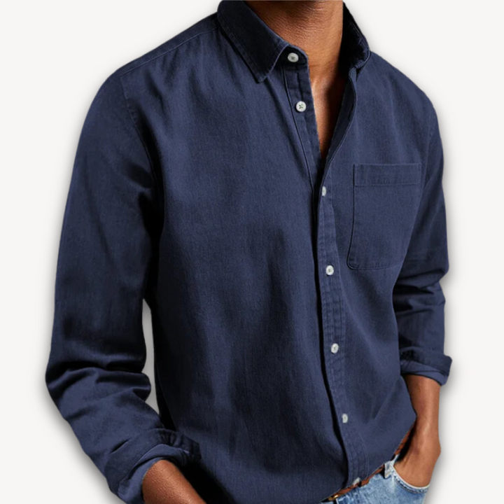 Navy blue long-sleeve button-up shirt with a classic collar and chest pocket, worn with light-wash jeans.