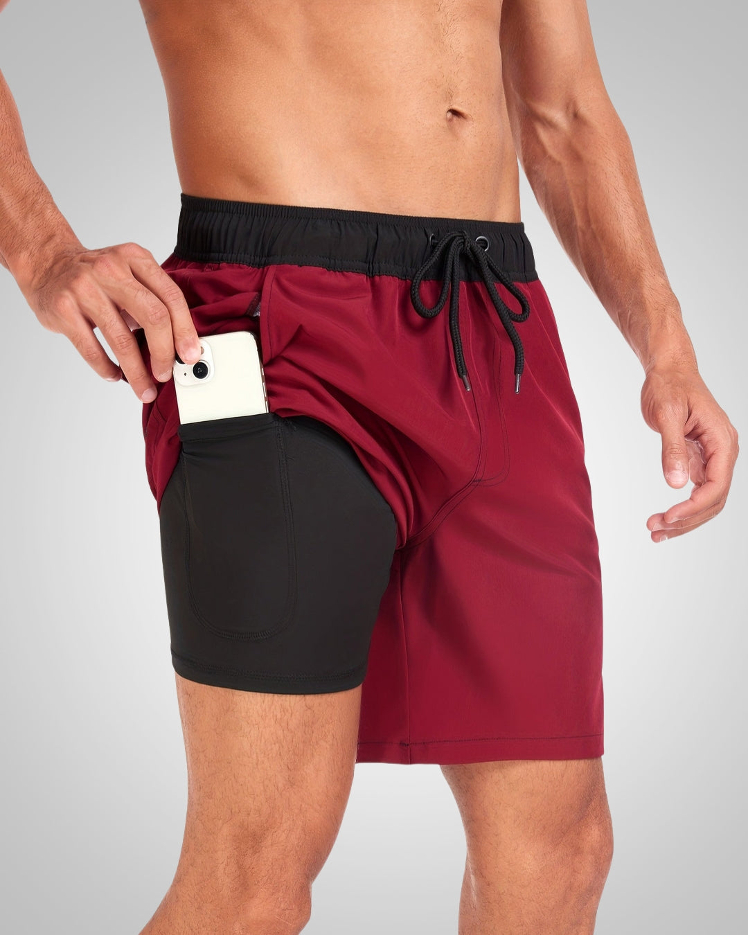 Burgundy men's swim shorts with a black drawstring waist and integrated black compression liner featuring a side phone pocket.