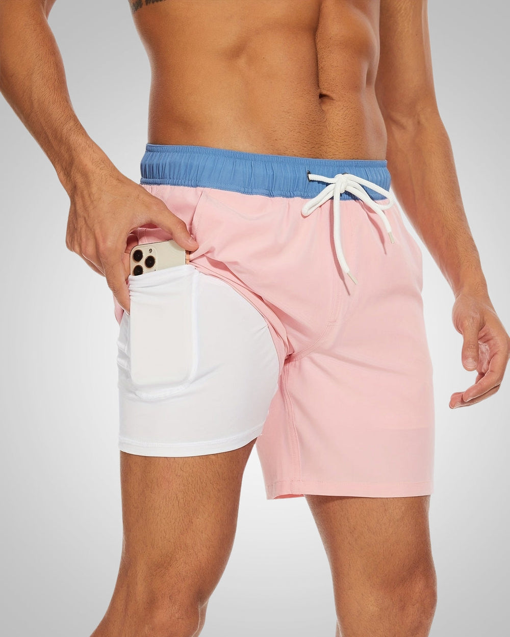 Pink and blue lined swim shorts with a white drawstring waist and a built-in inner pocket holding a smartphone.