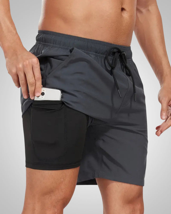 Charcoal grey men's swim shorts with a black inner liner, drawstring waist, and a side phone pocket on the leg.