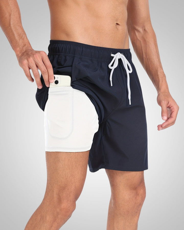 Navy blue swim shorts with a white inner liner, drawstring waist, and a side pocket holding a smartphone.