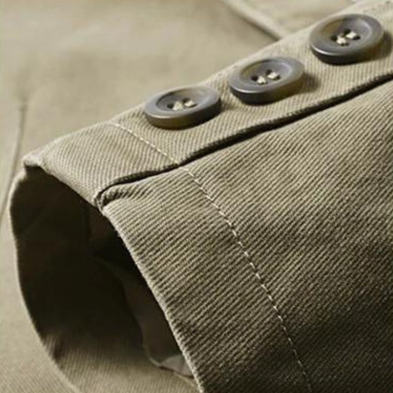 Close-up of a tan cotton casual blazer sleeve featuring three dark buttons and detailed stitching.