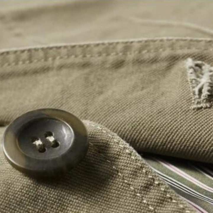 Close-up of a khaki cotton blazer featuring a dark button, stitched notch lapel, and striped inner lining detail.