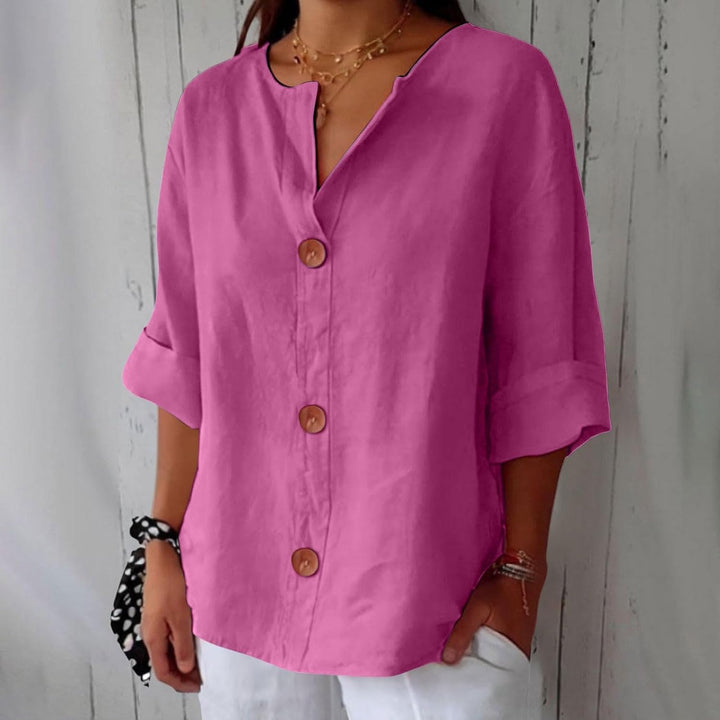 Magenta linen V-neck blouse with wooden buttons, relaxed fit, and rolled three-quarter sleeves.